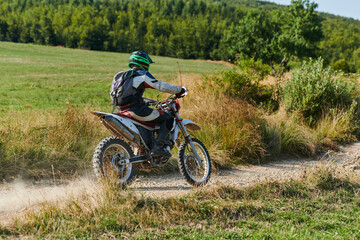 A professional motocross rider exhilaratingly riding a treacherous off-road forest trail on their...