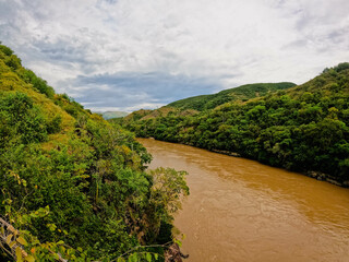 Fototapeta na wymiar Tranquil Colombia magdalena river flows down a picturesque hillside surrounded by lush trees