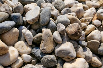 Closeup shot of lot of pebbles or river stones under sunlight on riverbank