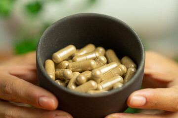 Ashwagandha capsules in a bowl, pills held in hand