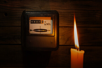 Candle in complete darkness looking on electricity meter at home -Energy crisis, power outage, high...