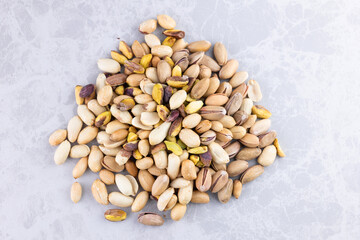 pistachios and peanuts mixed together in a circle on the marble countertop