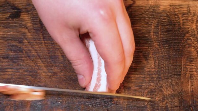 Slicing of salted pork fatback on cutting board, close-up. Ukrainian traditional food - salo