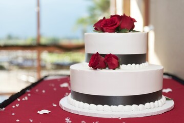 a large three tiered cake with red roses on top