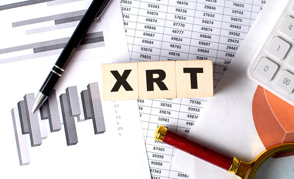 XRT text on wooden block on graph background with pen and magnifier