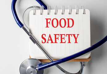 FOOD SAFETY word on notebook with medical equipment on background