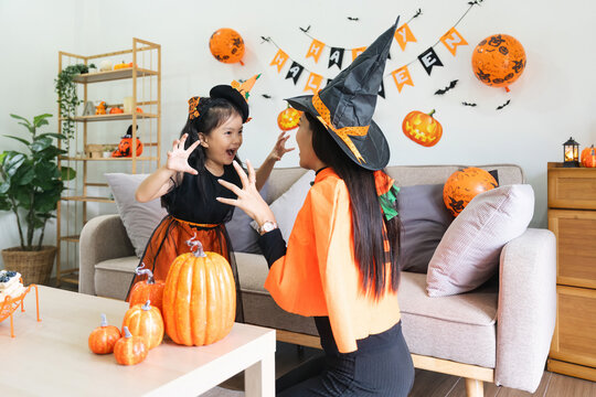Happy family mother and child happy girl with Halloween at home together beautifully decorated. Mother teasingly playing with daughter