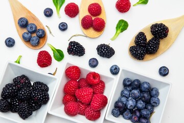 White plate containing different berries and spoons of berries