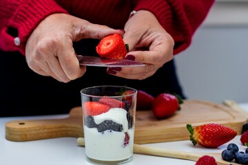 Person cutting a piece of fruit into a glass