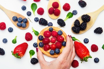 Woman holding a tart filled with fresh berries