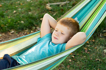 child boy relaxing in the hammock in the gadren at sunny summer day