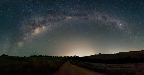 Night view of a road under milky way arch in the sky