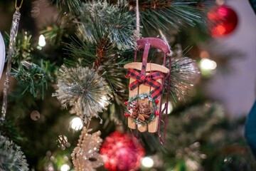 Small Christmas decoration hanging from the Christmas tree on the blurred background