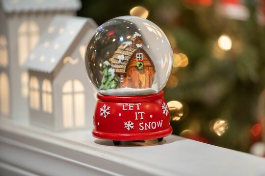 Small Christmas snow globe with a "Let it snow" text on it on the blurred background