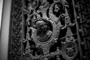 Black and white stock photo captures an ornamental metal door with intricate detailing