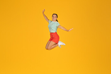 Carefree positive young woman jumping in the air on yellow