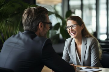 Fototapeta premium Portrait of happy businesswoman and businessman sitting at table in office