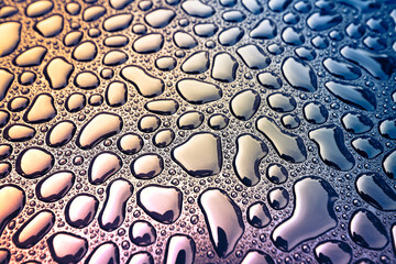 Abstract view of rain water drops on black metal surface, cross-processing effect applied