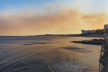 Evening in Portugal. Massive dry forest fire near the Cascais city. Thick dark smoke plumes...
