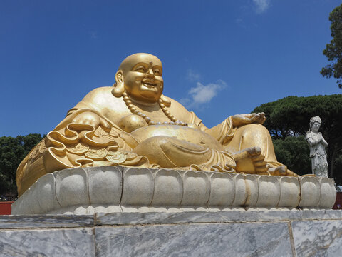 Large golden Laughing Buddha in the Bacalh&ocirc;a Buddha Eden park or Garden of Peace. Quinta dos Loridos, Portugal.