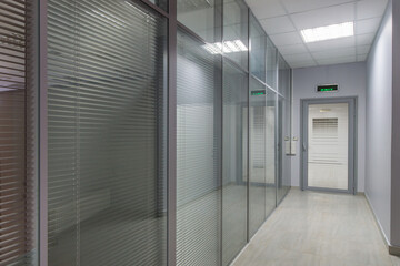 Office corridor in light blue tones with glass partitions.