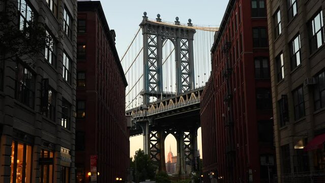 New York, USA - 3 September 2023: 4K wide angle video during a sunset over New York, view from Dumbo area in Brooklyn with Empire States landmark building under Manhattan Bridge.