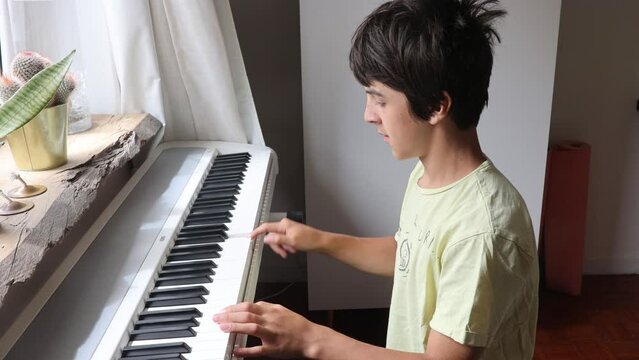 Cute child, boy, playing piano at home, learning how to play music
