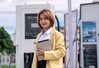 Businesswoman holding tablet examining quality charging station electric vehicle.