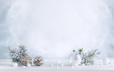 Christmas still life with snowy pine cones, baubles and  fir branches on light background. Winter or Christmas festive concept. - obrazy, fototapety, plakaty