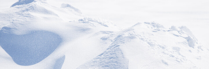 Obraz premium Beautiful winter background with snowy ground. Natural snow texture. Wind sculpted patterns on snow surface. Arctic, Polar region.