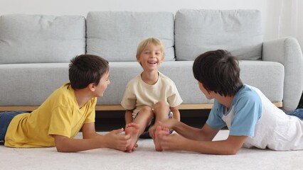Happy positive children, tickling on the feet, having fun together, boy brothers at home having wonderful day of joy together - Powered by Adobe