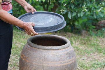 Fototapeta premium Closeup hands hold lid to cover water jar to protect from mosquitoes to breed inside or other insects or dust go into water. Concept, campaign to stop mosquitoes cycle to lay eggs in water container