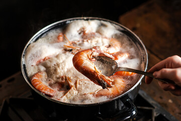 Large king prawns are boiled in a saucepan.