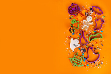 Bright colorful Halloween gingerbread cookies and sweet background. Homemade biscuits with cookie cutters, sugar sprinkles and candies. High-colored Halloween treats flat lay top view copy space