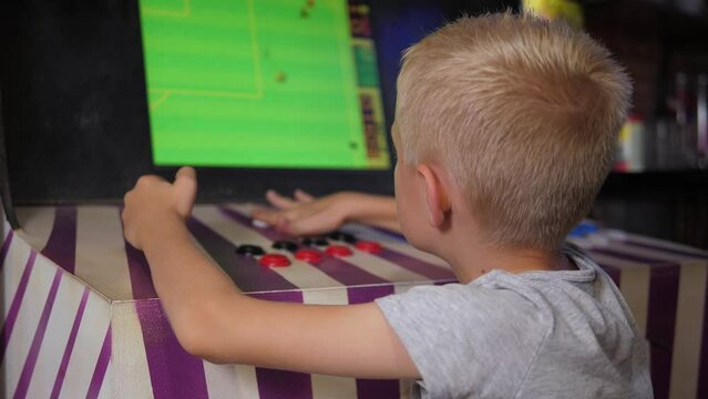 Close-up of a little boy playing a video game on an antique slot machine, green screen. A child is playing an antique video game.