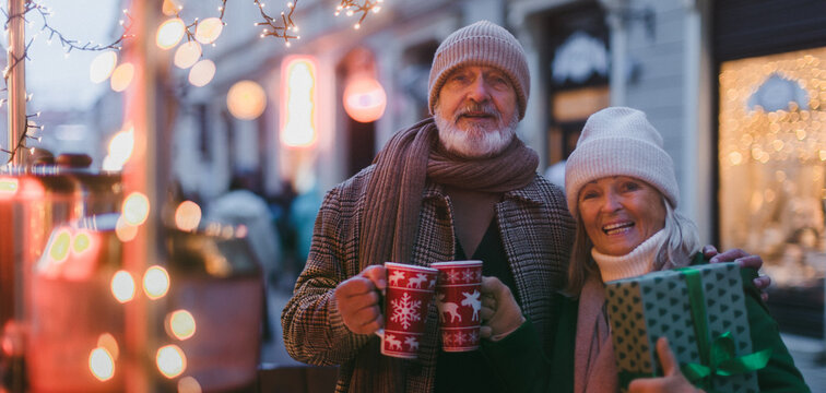 Happy senior couple enjoying christmas market, buying gifts.