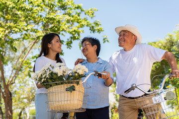 Happy and healthy Asian family standing beside a bicycle after workout together.  friendship lifestyle, Enjoyment of active seniors, outdoor activity after retirement, health care insurance concept.