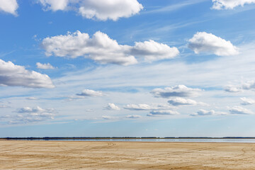Scenic summer landscape blue sky clouds, water surface and sandy shore. Minimal aesthetic nature view. Pastel colors cloudscape. Ulzhay (Uldjay) salt lake with medicinal mud in Omsk region