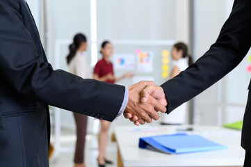 Two business partners shake hands after concluding a business finished in the office. Business to...