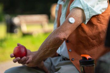 Close up of senior man with sensor of continuous glucose monitor on his arm. Elderly healthcare....