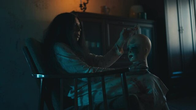 Crazy witch stroking creepy manikin head in dark room, psychopathic behavior