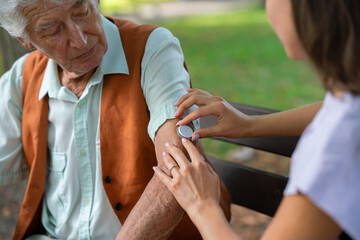 Caregiver helping senior diabetic man to apply continuous glucose monitor sensor on his arm. Senior...