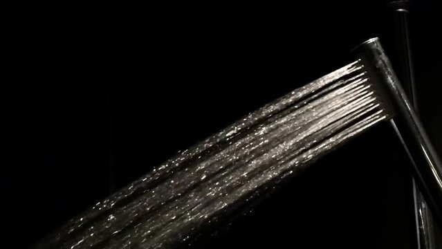 Footage water running from shower head faucet in dark background, back lit, turn on and tun off, take a shower, relax at night, water fly in the air