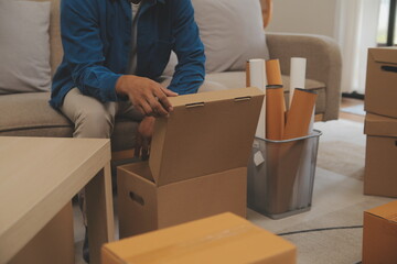 Beautiful young couple in love having fun unpacking things from cardboard boxes while moving in together in their new apartment