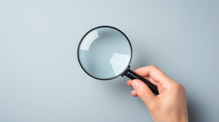 Hand holding magnifying glass on isolated light grey background