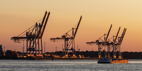 Containerbrückem am Athabaska-Kai im Hamburger Hafen bei Sonnenuntergang mit einem kleinen Tanker.