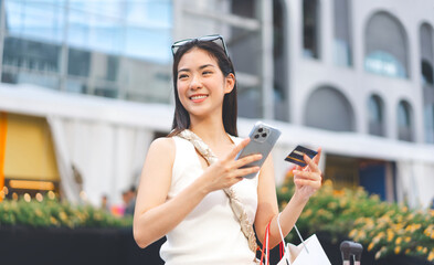 Elegant asian woman using electronic mobile banking app and credit card at outdoors