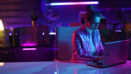 Neon metaverse futuristic concept. stylish woman in glasses using laptop in modern office.