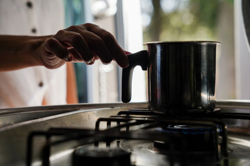 Female hand putting a kettle on the gas stove with hot drink in a van. wellness in the field