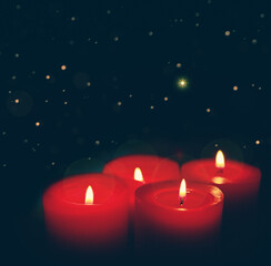 Four burning red Advent candles on black background.